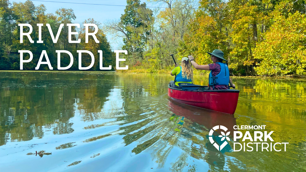 The words "River Paddle" are written in the top left corner of the image. The image shows two people in a red canoe, wearing life jackets. We see them from the back. The canoe floats on still water, w